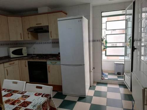 um frigorífico branco numa cozinha com piso em xadrez em PISO 4 HABITACIONES BURJASOT em Burjassot