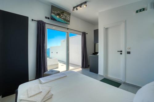 a bedroom with a white bed and a large window at Akrogiali Apartments in Barbati