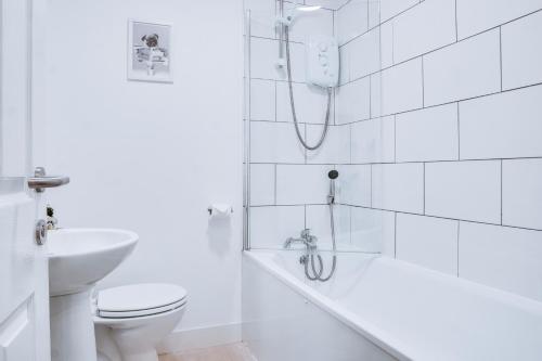 La salle de bains blanche est pourvue d'une baignoire et de toilettes. dans l'établissement Birkenhead - 2 bedroom house, à Birkenhead