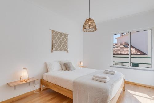 a white bedroom with a bed and a window at Alta do Garajau I in Caniço