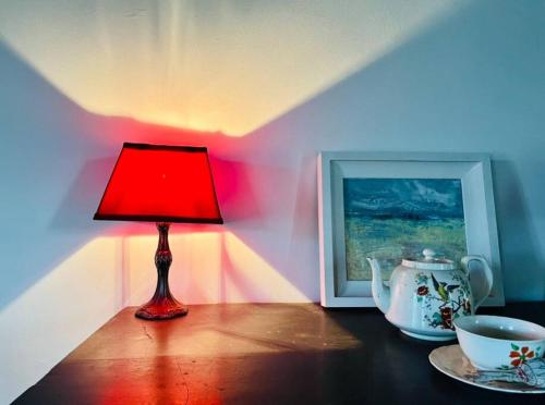 una lámpara roja sentada en una mesa junto a una foto en Traditional Donegal house on the Wild Atlantic Way en Burtonport