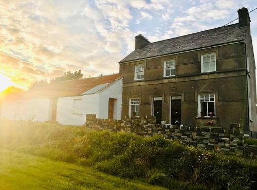 ein altes Haus auf einem Hügel mit Sonnenuntergang in der Unterkunft Traditional Donegal house on the Wild Atlantic Way in Burtonport