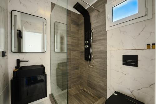 a bathroom with a shower with a sink and a mirror at Akrogiali Apartments in Barbati