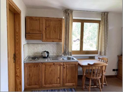 a kitchen with wooden cabinets and a table and a window at Plose Parkhotel - Residence in Plancios