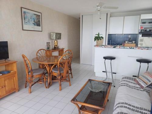 ein Wohnzimmer mit einem Tisch und Stühlen sowie eine Küche in der Unterkunft Le Bel Air in Canet-en-Roussillon