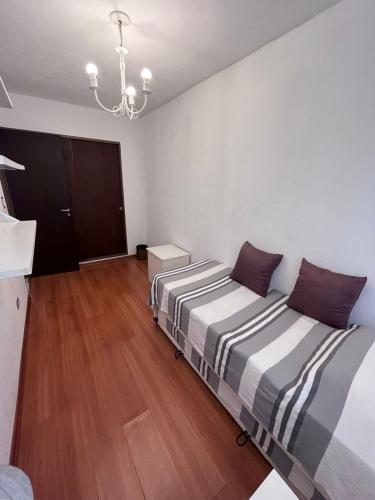 two beds in a room with wooden floors and a chandelier at Corazón de Vicente López in Vicente López