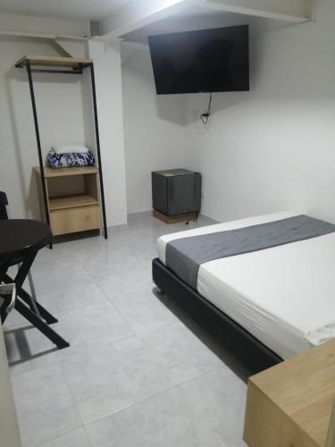 a bedroom with a bed and a desk and a tv at Hotel Urbano 70 in Medellín