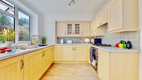 a kitchen with wooden cabinets and a large window at Super-Quiet Town Centre Flat 5 min Walk to Station in Royal Tunbridge Wells
