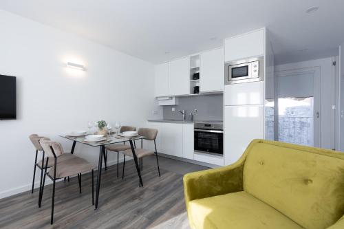 a kitchen and dining room with a yellow couch and a table at Dona Emília Studio Apartments in Viana do Castelo
