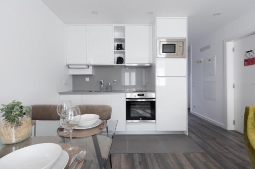 a kitchen with white cabinets and a table and chairs at Dona Emília Studio Apartments in Viana do Castelo