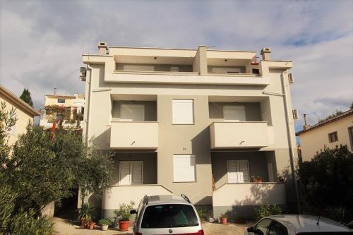 Un edificio blanco con un coche aparcado delante. en Apartments Karma, en Novalja
