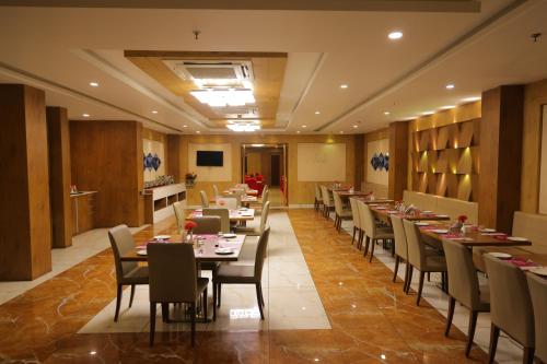 a restaurant with tables and chairs in a room at Regenta Central Somnath, Bhalpara in Somnath