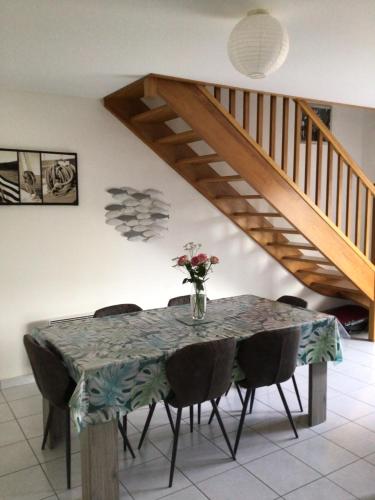 a dining room table with a vase of flowers on it at Maison Caroual Erquy 500m de la PLAGE in Erquy