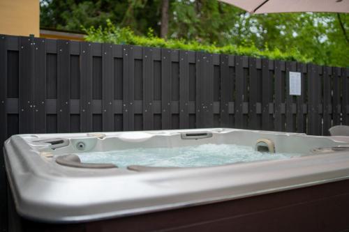 Accomo Apartmanház في سيوفوك: حوض استحمام ساخن يجلس أمام السياج