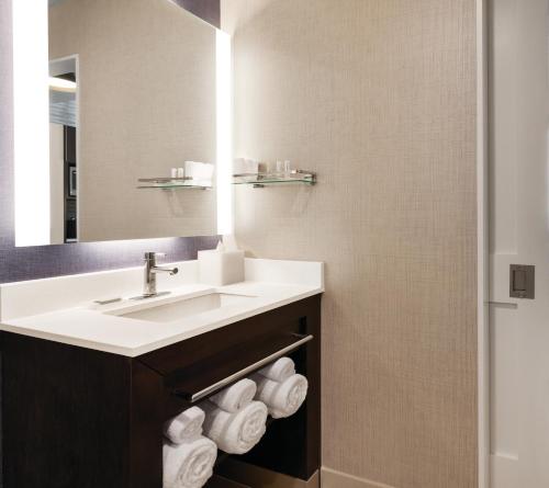La salle de bains est pourvue d'un lavabo, d'un miroir et de serviettes. dans l'établissement Residence Inn by Marriott New York JFK Airport, à Queens