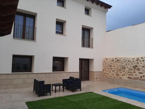 a white building with chairs and a swimming pool at Casa Rural Triticum in Navas de Bureba