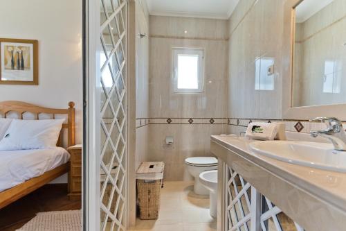 a bathroom with a sink and a toilet and a bed at BmyGuest - Lagoa Beach & Pool Villa in Lagoa de Albufeira