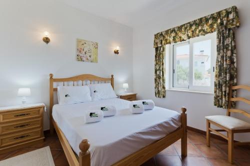 a bedroom with a bed and a chair and a window at BmyGuest - Lagoa Beach & Pool Villa in Lagoa de Albufeira