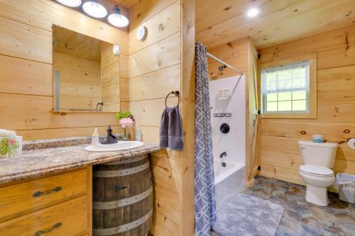een badkamer in een blokhut met een wastafel en een toilet bij Stunning North Rose Retreat with Fishing Pond! 