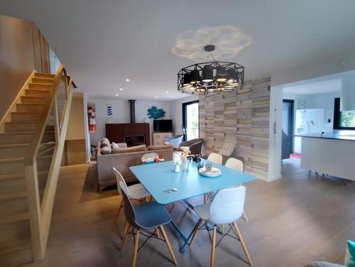 ein Esszimmer und ein Wohnzimmer mit einem blauen Tisch und Stühlen in der Unterkunft Superbe Villa d'architecte à 2 pas de la mer in Clohars-Carnoët