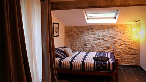 une chambre avec un lit et un mur en pierre dans l'établissement Esclarmonde 18, à Cascastel-des-Corbières