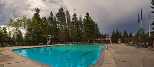 a large blue swimming pool with chairs and trees at Jackson Lake Lodge in Moran