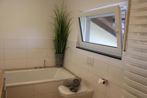 een badkamer met een bad, een toilet en een plant bij Ferienhaus mit eigenem Garten und Terrasse in Lindau-Bodolz