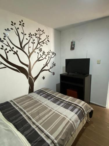 a bedroom with a tree stenciled on the wall at Casa Verde Hostal in Tlazcalancingo