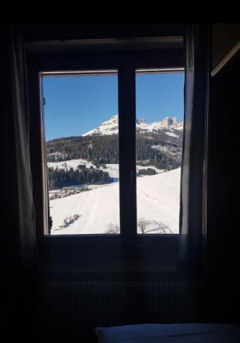 a window with a view of a snow covered mountain at Ciasa Alpina Relax Hotel in Moena
