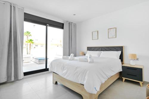 a white bedroom with a large bed and a large window at Villa Luna in San Pedro del Pinatar
