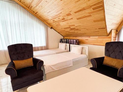 um quarto com uma cama e duas cadeiras em Gabala Mountain Lodge em Gabala