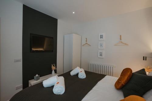 a bedroom with a bed with white pillows and a tv at Blooms Apartment in Marple