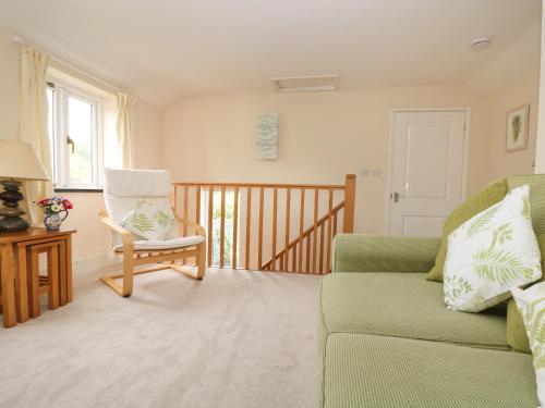 sala de estar con sofá verde y silla en Little Hamlin, en Callington