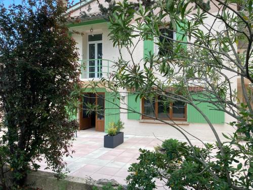 a green and white house with a courtyard at Pavillon de l’Étang in Châteauneuf-du-Rhône