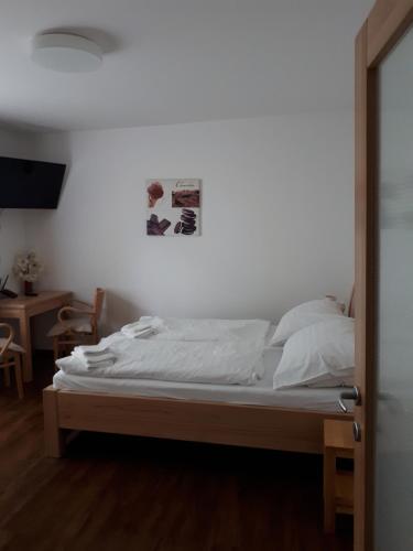 um quarto com uma cama com lençóis brancos e uma mesa em Depandance Blatov em Praga