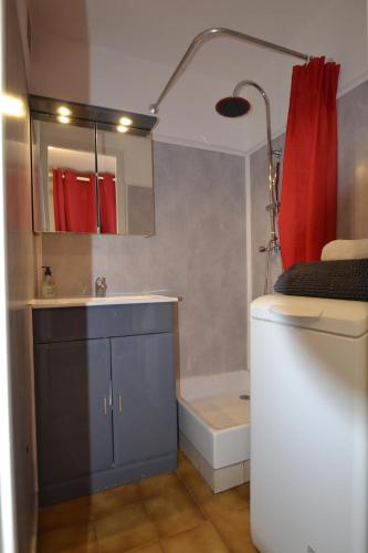 een badkamer met een wastafel en een rood douchegordijn bij Villa Naturiste "EDEN" Héliovillage 105 in Cap d'Agde