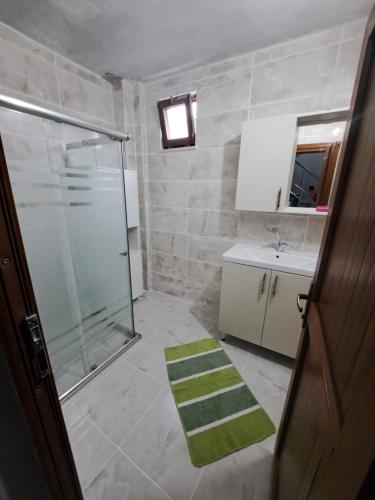 a bathroom with a shower and a green rug at ORTAKÖY VİLLA in Macka