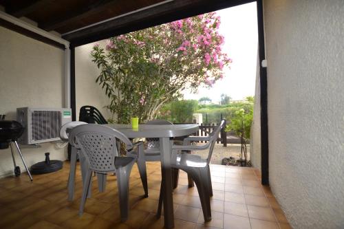 een tafel en stoelen op een patio met uitzicht op een boom bij Villa Naturiste "EDEN" Héliovillage 105 in Cap d'Agde