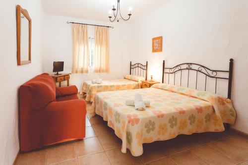 a hotel room with two beds and a chair at Villa la Dehesa in Conil de la Frontera