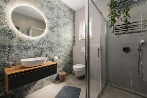 a bathroom with a sink and a shower with a mirror at Villa Istra Maružini by Solis Porec in Maružini