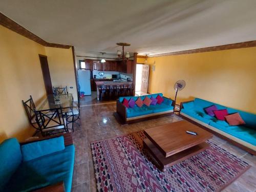 sala de estar con sofá azul y mesa en Chalet in Mena 4-North Coast, en Dawwār ‘Abd al ‘Aţī Abū ‘Ajūz