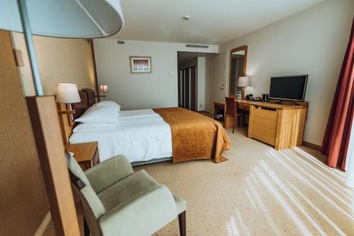 a hotel room with a bed and a desk and a television at Gabija Hotel SPA & Conferences in Palanga