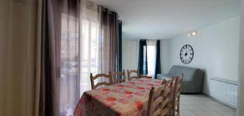 une salle à manger avec une table et une horloge au mur dans l'établissement OPEN, Grand T2, 47m2, 6 couchages, 2 salles de bai, à Fréjus