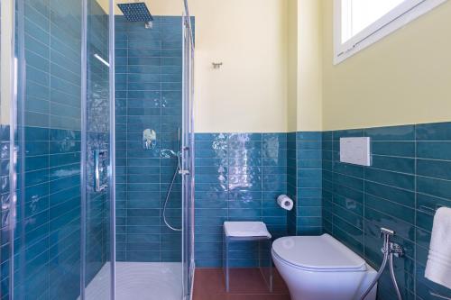 y baño de azulejos azules con aseo y ducha. en Fani Rooms, en Salve