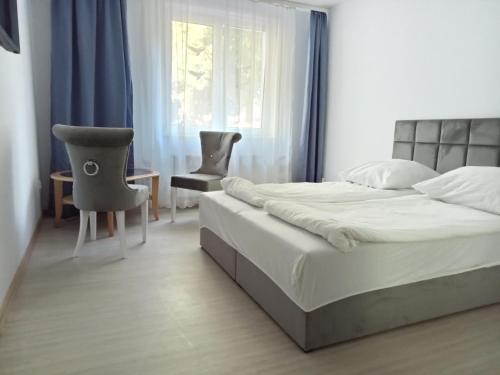 a bedroom with a bed and two chairs and a window at Willa Aqua, Parkplatz inklusive in Świnoujście