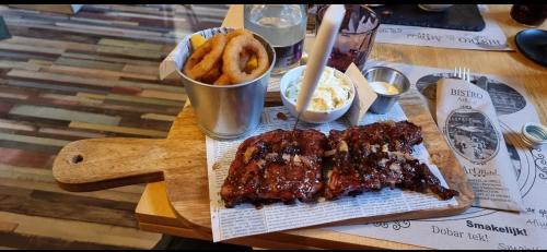 a wooden table with ribs and french fries on it at ArtMotel & Bistro in Haţeg
