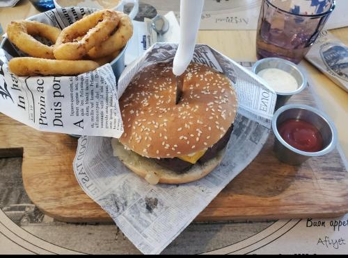 a hamburger and onion rings on a cutting board at ArtMotel & Bistro in Haţeg