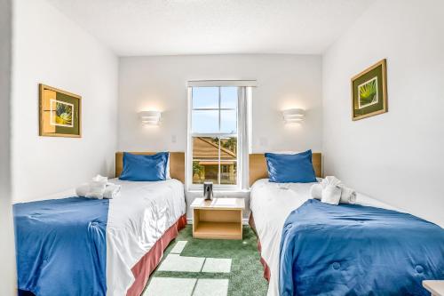 two twin beds in a room with a window at Bright & Breezy in Kissimmee