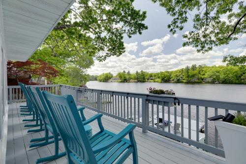 a row of blue chairs on a porch overlooking the water at Football Fans Lake Retreat - 5 Mins to Gillette! in Plainville