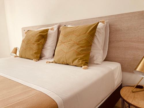 a bed with two gold pillows on top of it at Pavillon de l’Étang in Châteauneuf-du-Rhône
